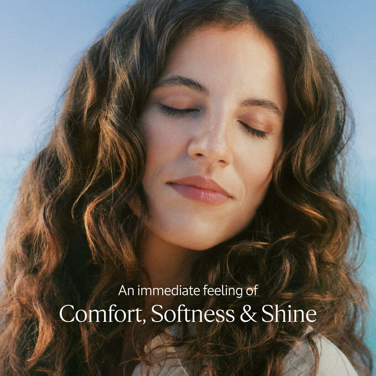 Woman with curly hair enjoying comfort, softness, and shine in a natural setting.