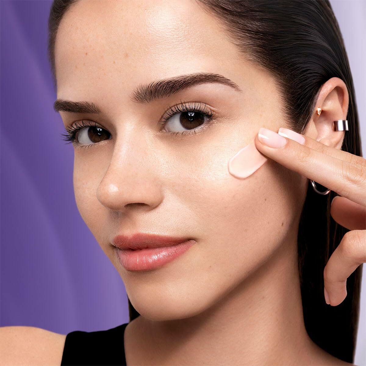 Woman applying Lancôme RÉNERGIE facial cream with SPF 50, showcasing radiant skin in a well-lit setting.