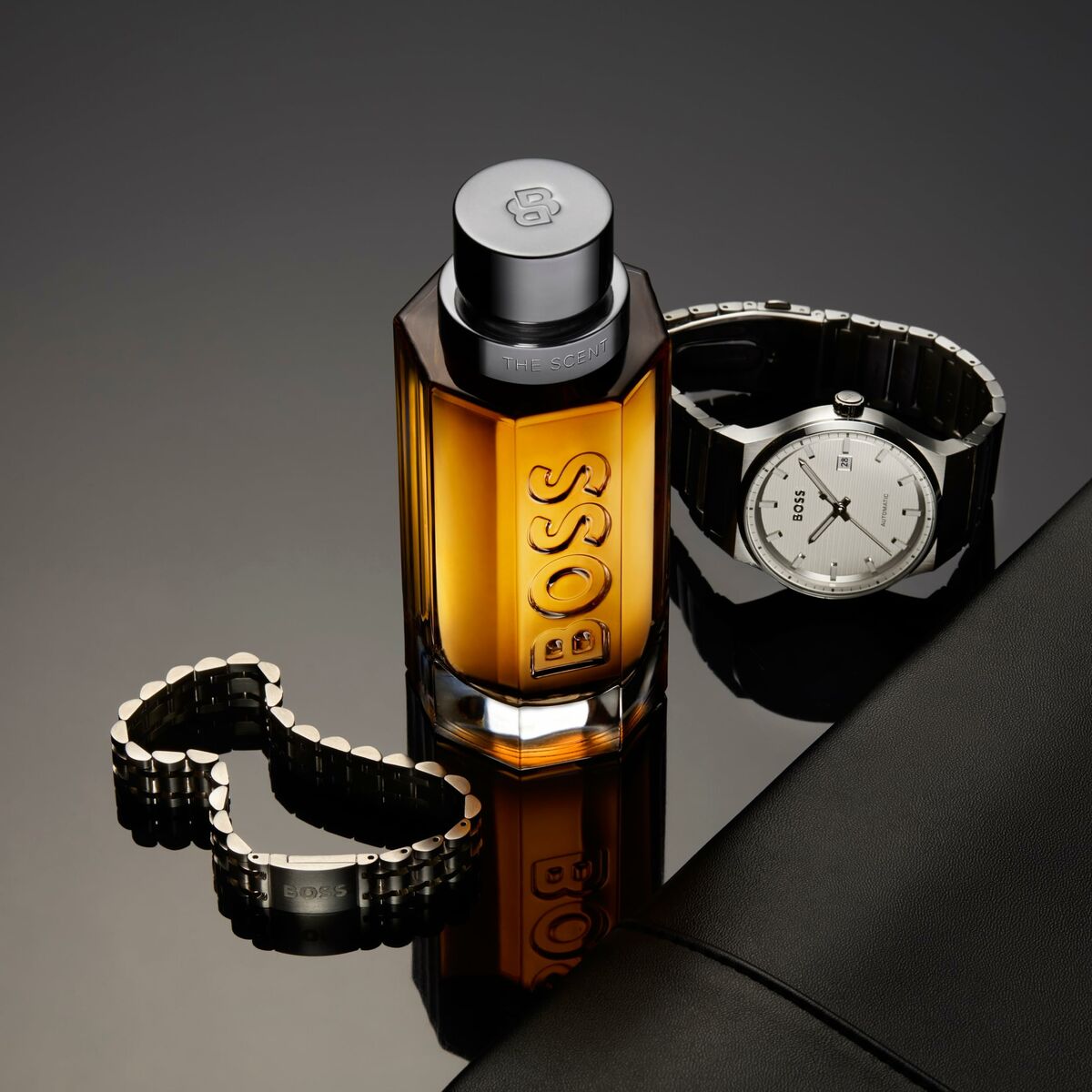 Hugo Boss THE SCENT 200 ml bottle with stylish watch and bracelet on a sleek black background.