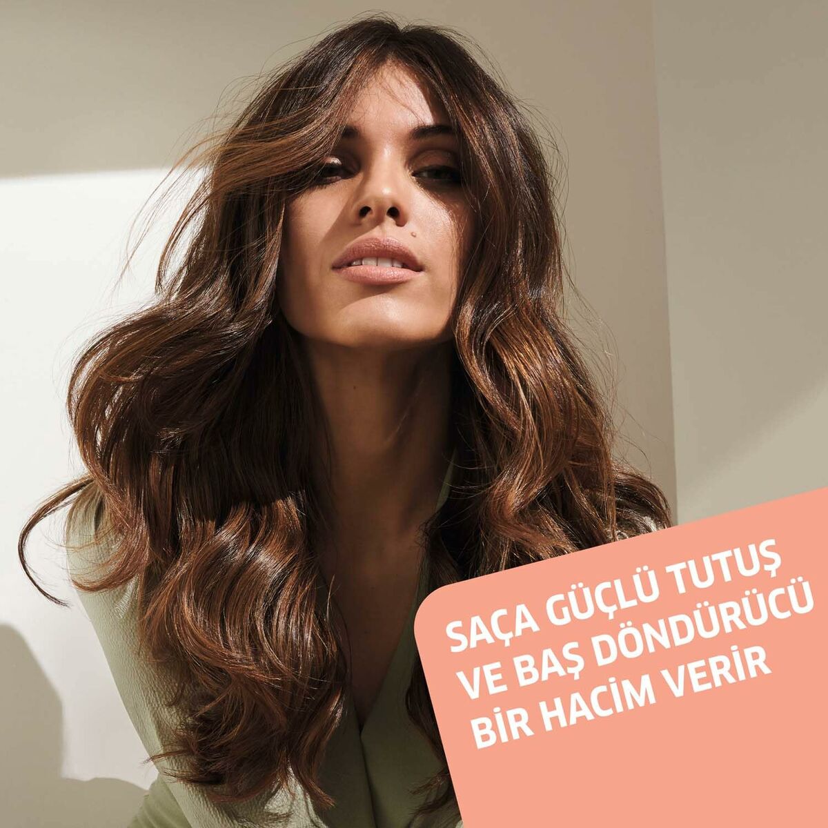 Femme avec des cheveux volumineux et brillants, mettant en avant la mousse volumatrice Wella EIMI VOLUME.